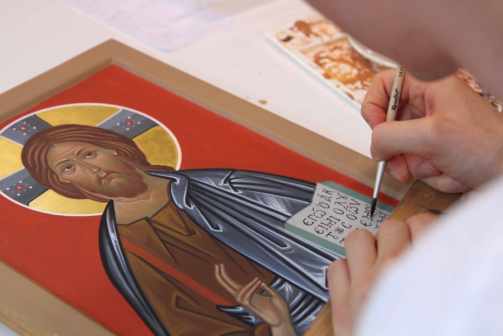 Allievo al lavoro su un'icona di Cristo durante un corso
